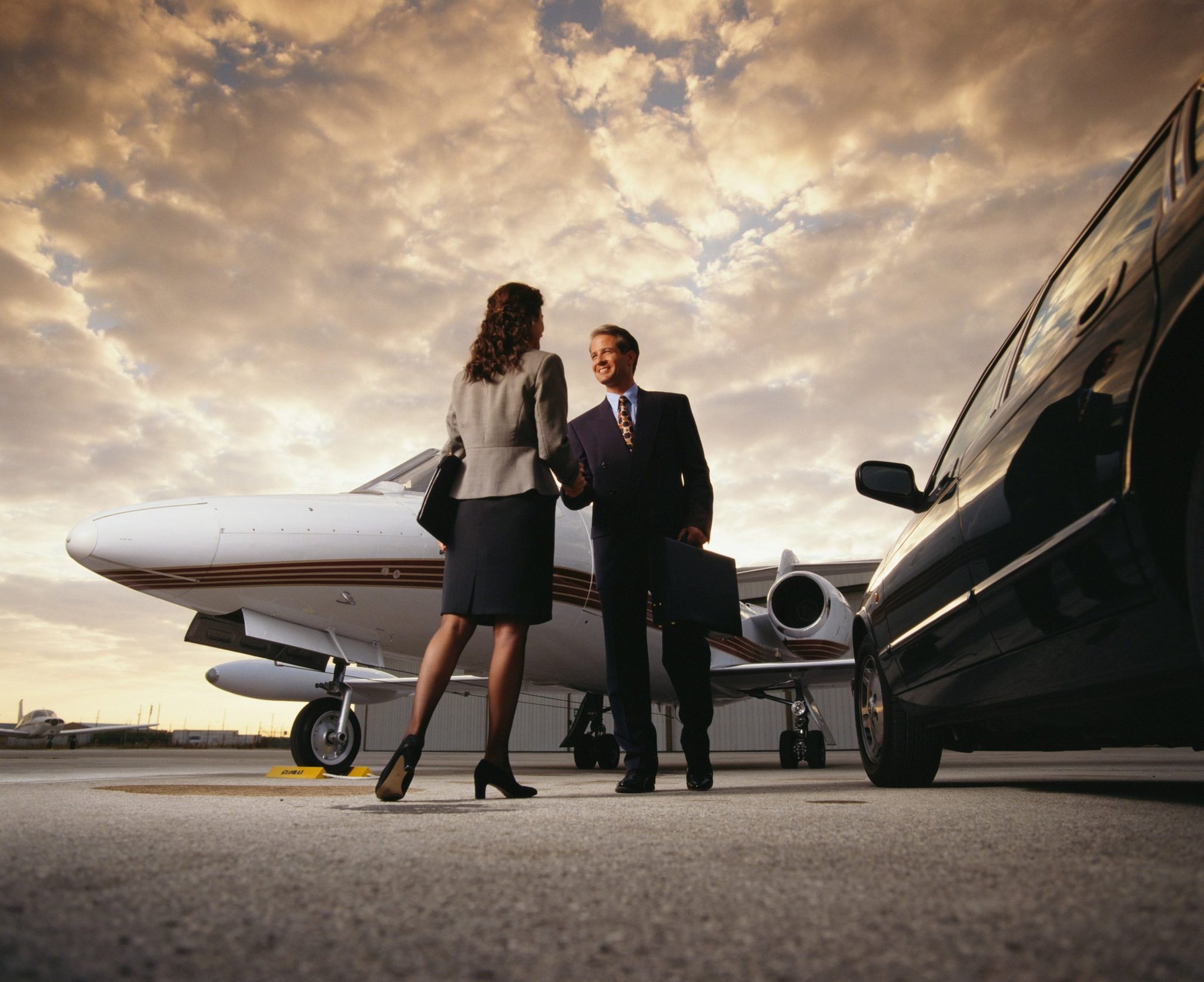 Two travellers walking to a private jet at sunset